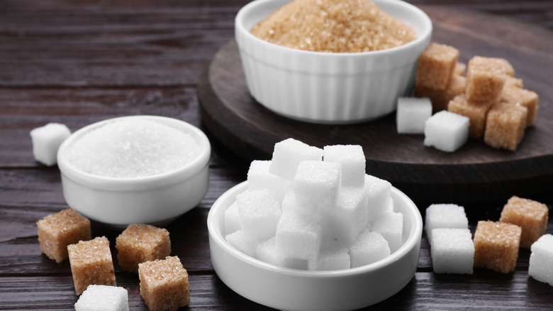 Different types of sugar on a wooden table.