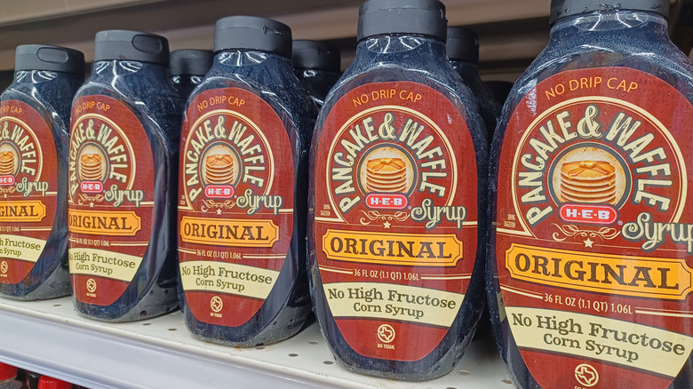 Bottles of pancake syrup with the label "no high fructose corn syrup" written in bold letters sitting on the grocery store shelf.