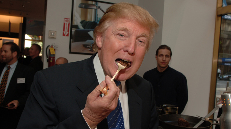 Donald Trump eating steak with a golden fork at what seems like an event
