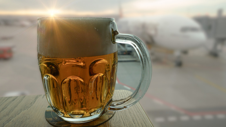 Cold beer with view of a plane at an airport