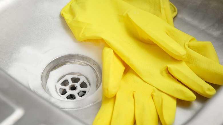 preparing to clean a stinky drain in kitchen sink with gloves