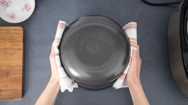 Someone holds an upside down pie dish by the sides using towels