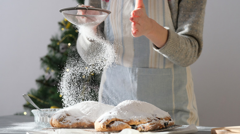 Someone dusts sugar over pastries