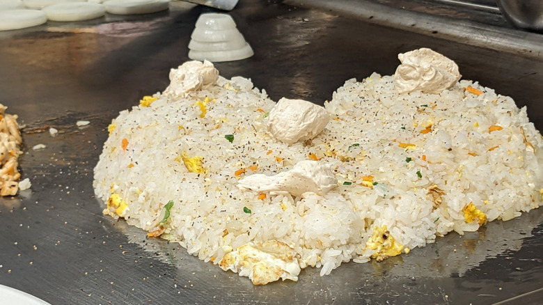 Benihana fried rice topped with garlic butter on a grill surface