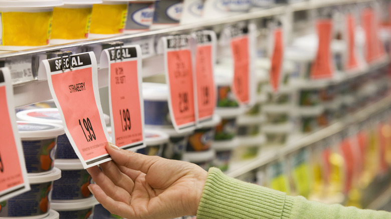 A person inspecting a sale tag posted on a grocery store shelf