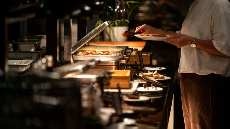 A guest building a plate at a buffet