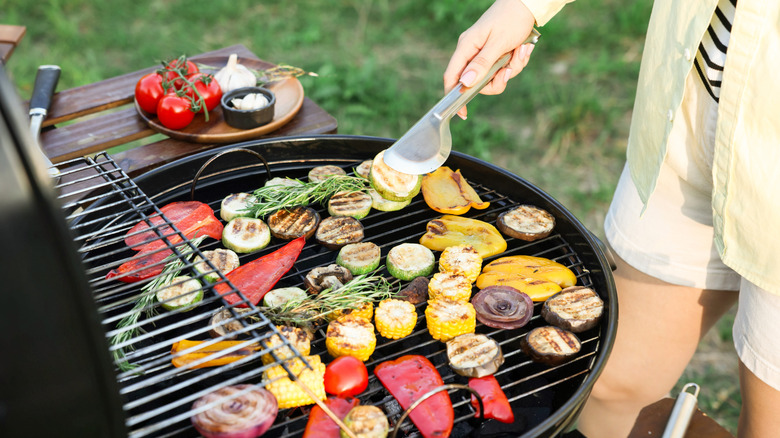 woman grill veggies over charcoal grill outside