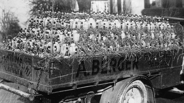 Vintage 1930s black and white image of Chianti bottles stacked on the back of a truck.