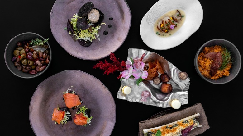 Several plates of decorated food on a black backdrop