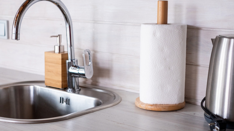 Closeup of paper towel roll on a kitchen counter with stainless steel sink and appliance