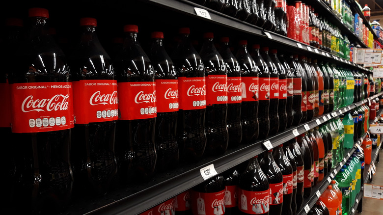 coca cola bottles lined up on shelf