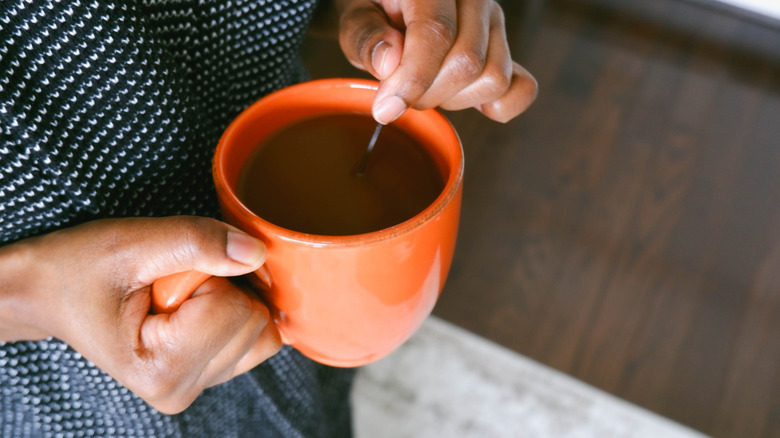 Person stirring a cup of coffee