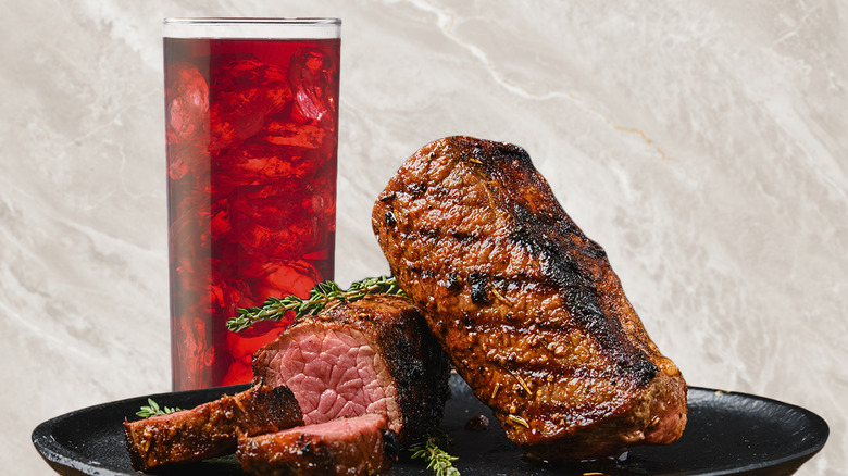 Cranberry juice next to a steak 