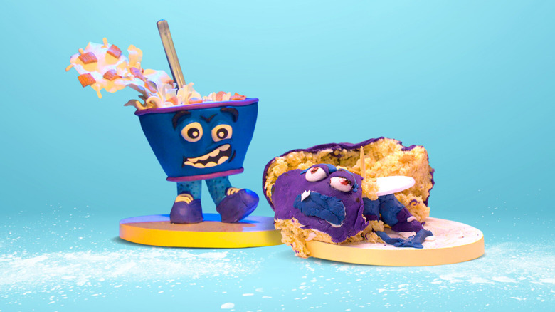 A cake shaped like an anthropomorphic blue and purple cereal bowl with a face and two feet next to a mangled, horribly made version of the same cake on "Nailed It!"