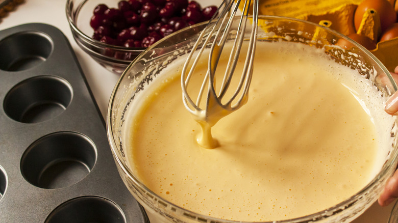 Overhead view of person whisking together vanilla cake mix in a mixing bowl
