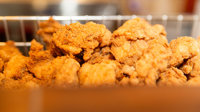 Close-up up fried chicken pieces in a wire basket.