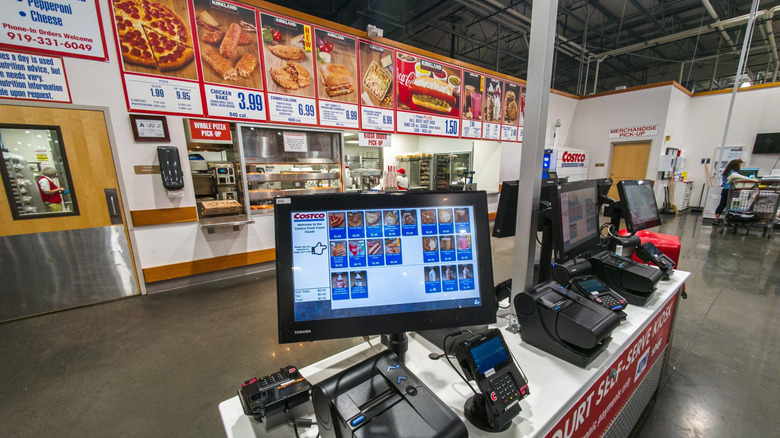 Costco food court display kiosk showing an electronic order screen featuring pepperoni pizza, drinks, hot dogs, ice cream and more