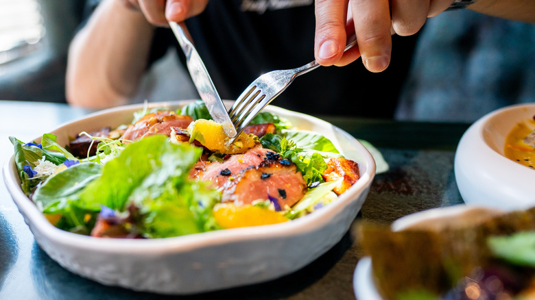 Salmon salad eaten with fork and knife