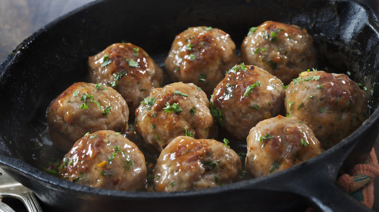 seasoned, cooked meatballs in a cast-iron pan