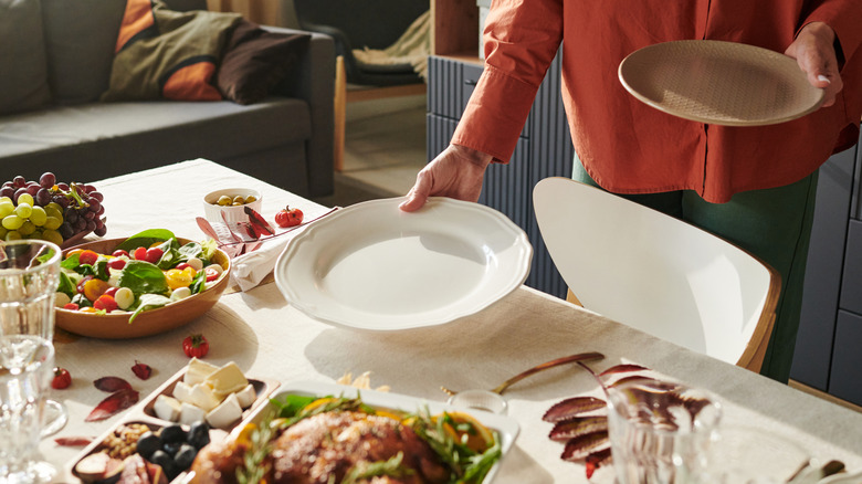 person putting plates on table with food