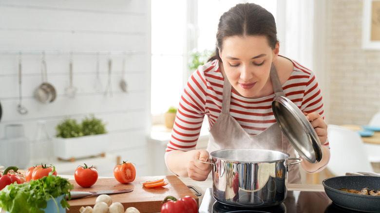 A woman smelling the aroma of food cooking in a pot