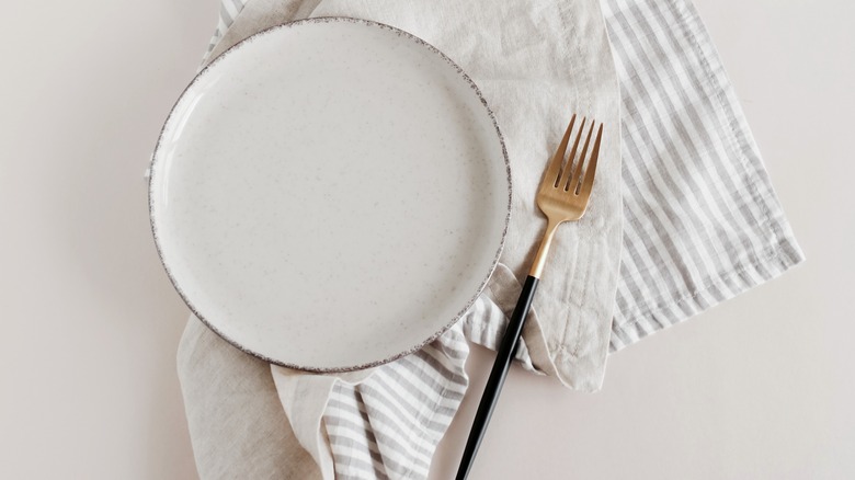 White plate and gold fork on napkin