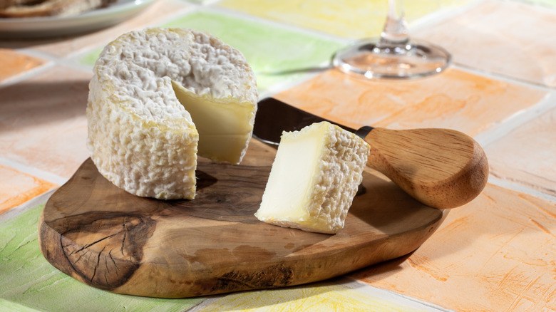 round of aged goat's cheese on a wooden cutting board