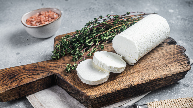log of goat cheese with thyme on cutting board