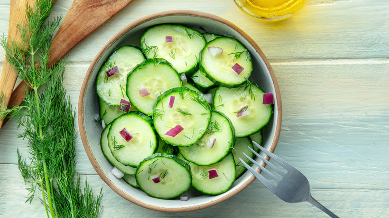 Overhead view of bowl of sliced cucumber salad on a table