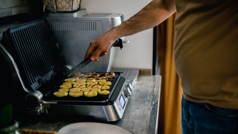 Man grilling zucchini on countertop grill