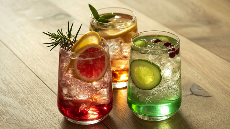 Three different gin and tonic drinks on wood