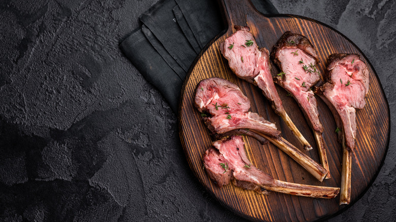 Overhead view of cooked medium rare lamb chops on wooden board