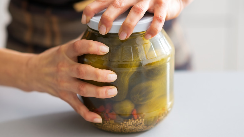 Hands opening a jar ofpickles