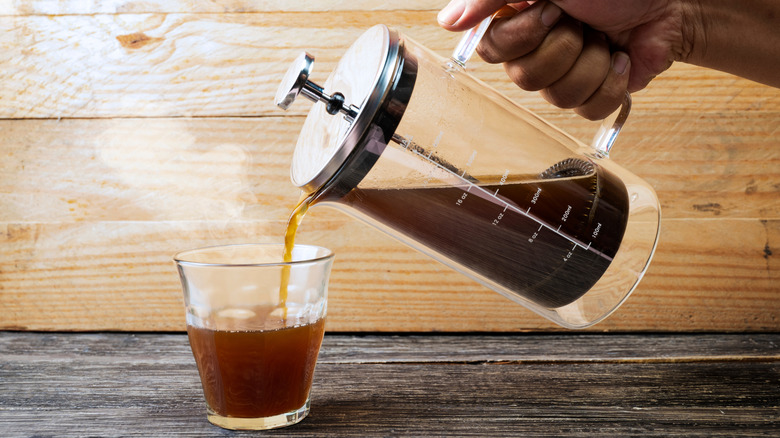 Person pouring French press coffee into a glass
