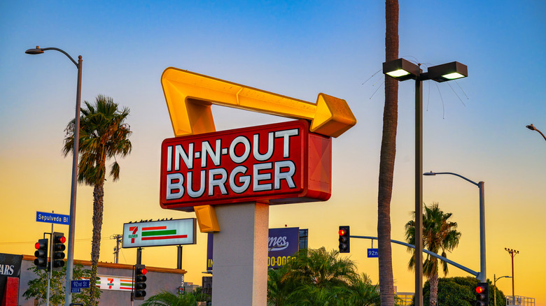 In-N-Out burger sign with palm trees in the background at sunset
