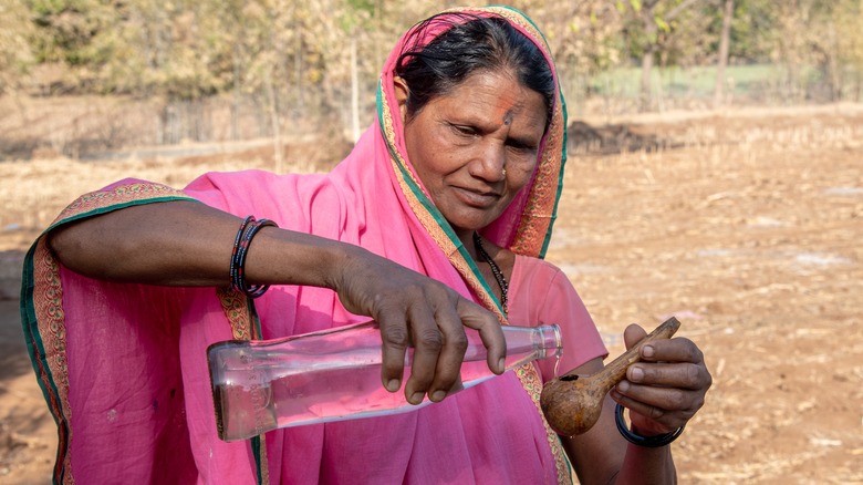 Indian woman pouring mahua liquor
