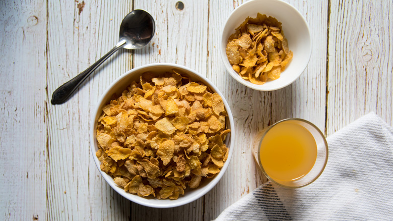 Two bowls of dry cereal and a glass of orange juice