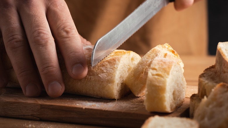 Serrated knife cutting through bread 