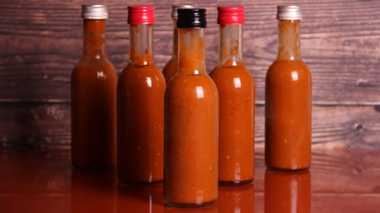 Several bottles of red hot sauce on a counter