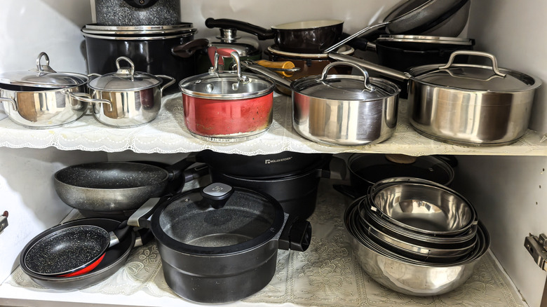 Kitchen cabinet filled with assorted pots and pans