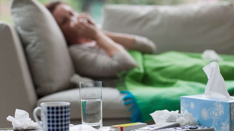 Person on the couch sick with water and tissues
