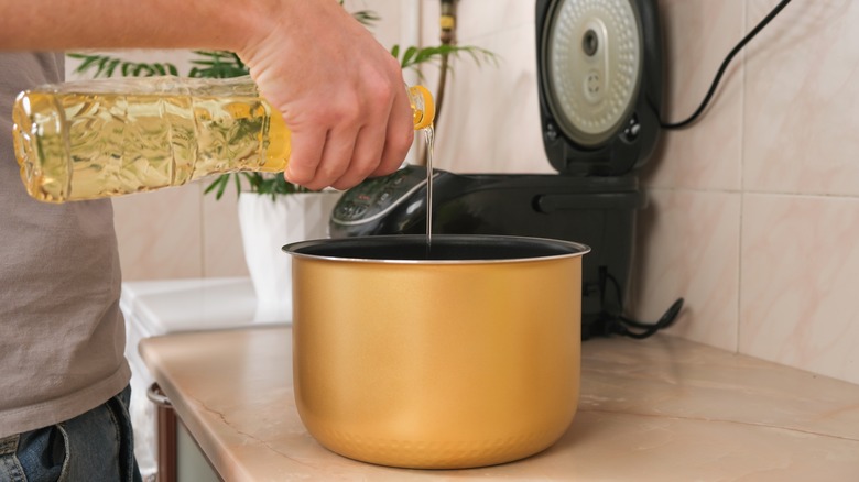 man pouring oil in pressure cooker