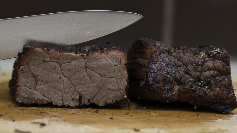 knife cutting into overcooked steak