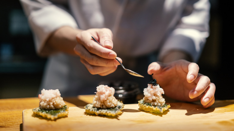 Chef plating appetizers with spoonfuls of caviar