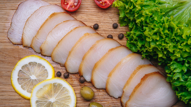 Sliced escolar with greens, lemons, olives and pepper