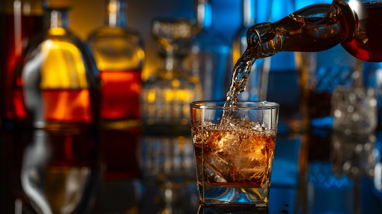pouring whiskey into glass on bar