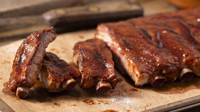 Cooked spare ribs coated with barbecue sauce on brown parchment paper