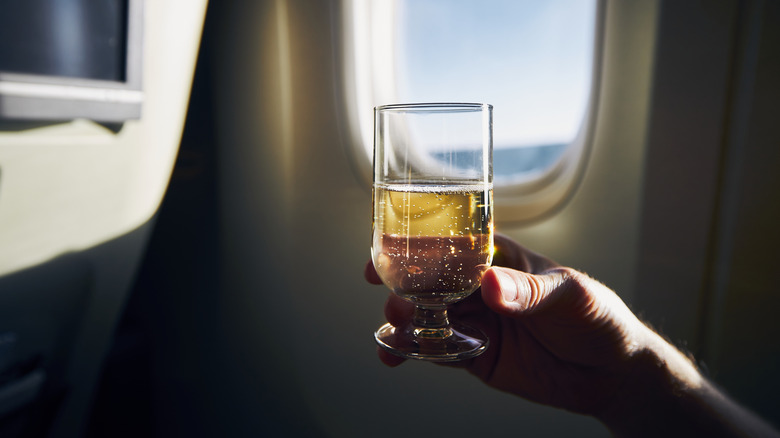 person holding wine glass in front of plane window
