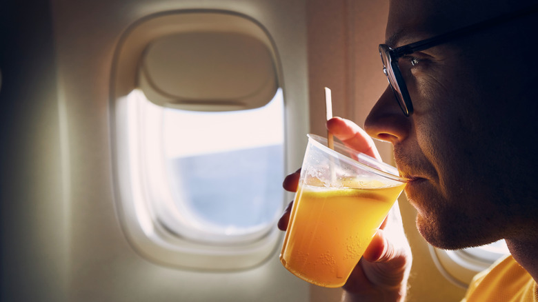 person holding cocktail in front of plane window