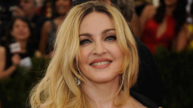 Madonna smiles at a public function, with members of the press standing in the backdrop